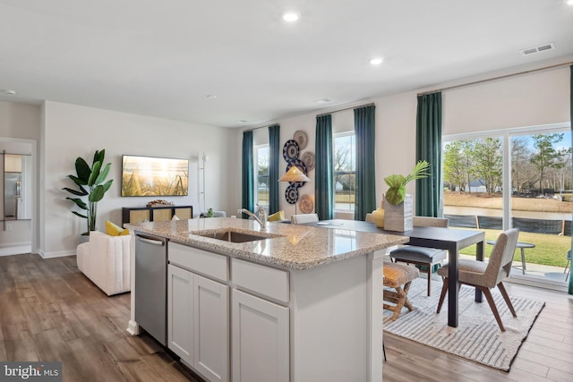 kitchen featuring light stone countertops, visible vents, a sink, and wood finished floors