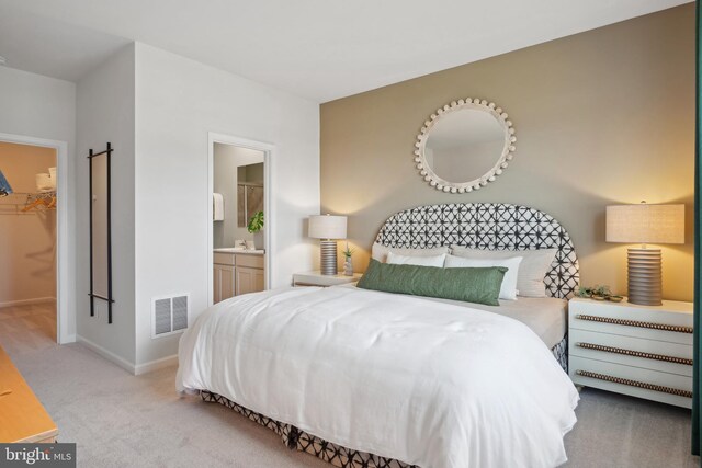 carpeted bedroom featuring connected bathroom, visible vents, baseboards, a closet, and a walk in closet