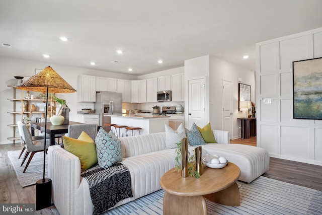 living area featuring recessed lighting, a decorative wall, and light wood finished floors