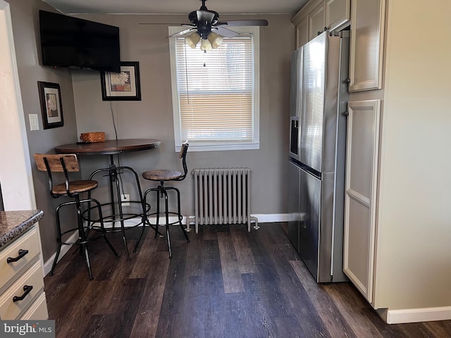 dining space featuring baseboards, dark wood-style flooring, a ceiling fan, and radiator