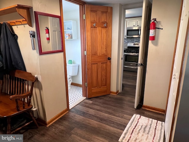 corridor featuring dark wood-style floors and baseboards