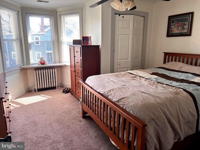 carpeted bedroom featuring crown molding, baseboards, visible vents, and radiator