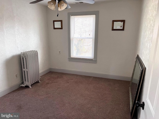 empty room with carpet floors, radiator, ceiling fan, and baseboards