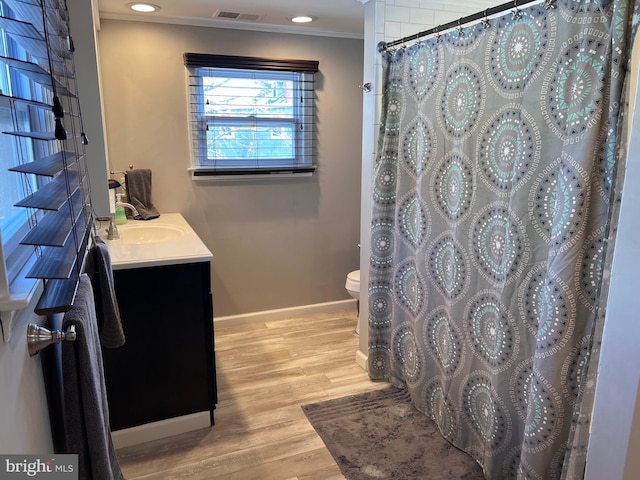 bathroom featuring toilet, wood finished floors, visible vents, baseboards, and crown molding