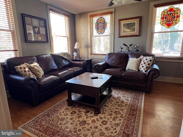 living area featuring wood finished floors, a ceiling fan, and baseboards