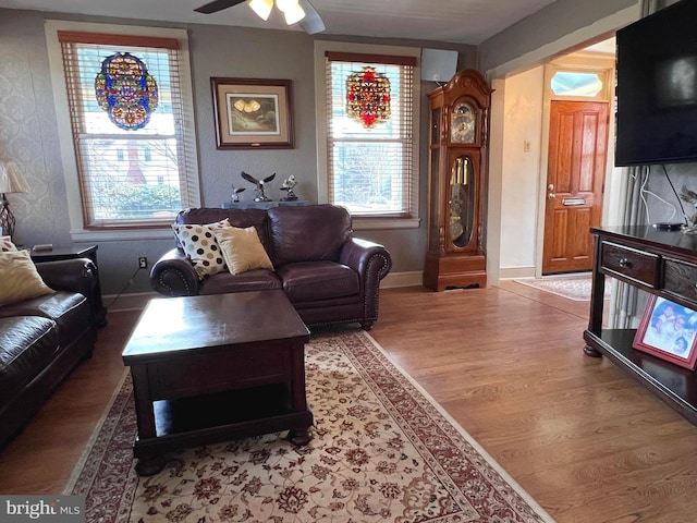 living area with a ceiling fan, baseboards, and wood finished floors