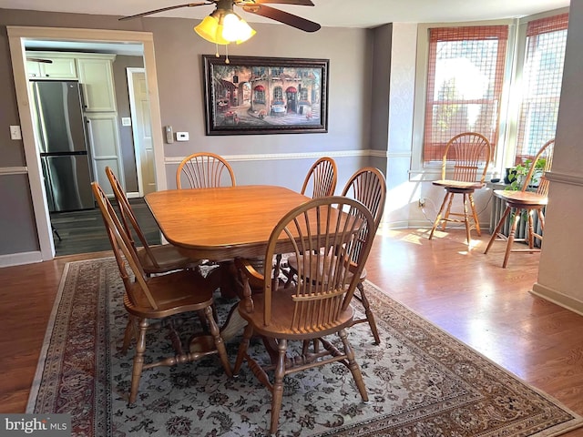 dining space featuring a ceiling fan, baseboards, and wood finished floors