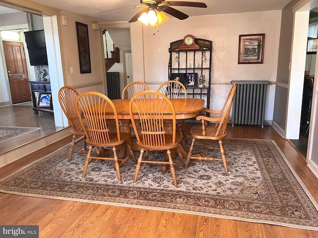 dining room with radiator, ceiling fan, baseboards, and wood finished floors