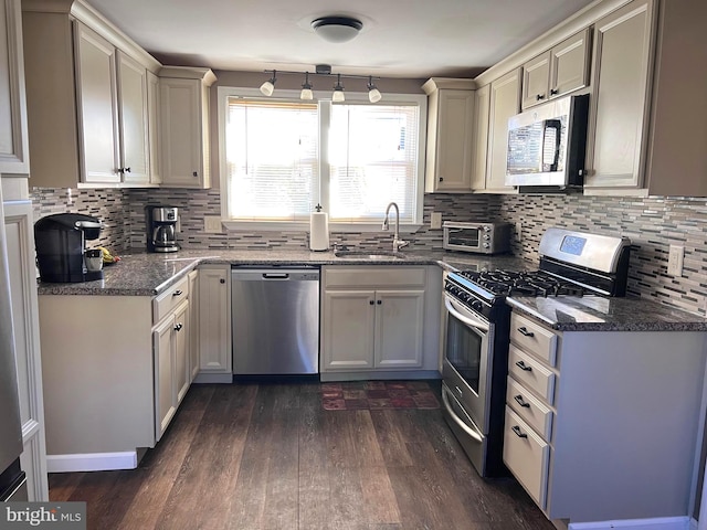 kitchen featuring appliances with stainless steel finishes, dark wood-style flooring, a sink, and decorative backsplash