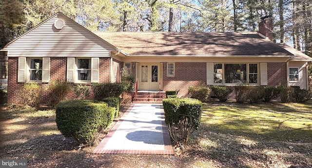 view of front of house with brick siding, a chimney, and a front lawn