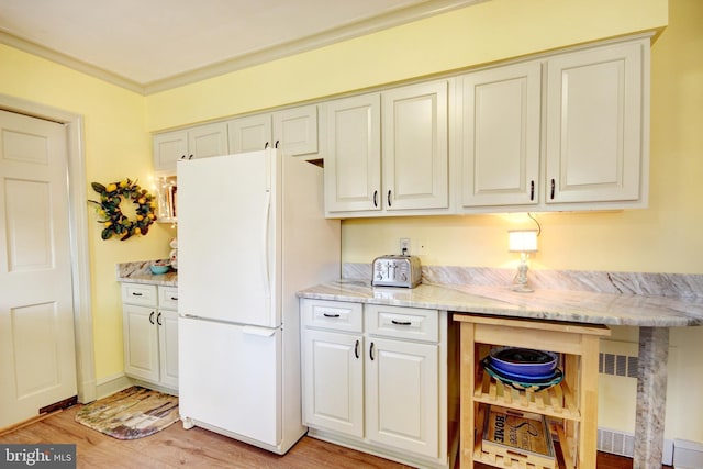 kitchen featuring ornamental molding, freestanding refrigerator, light wood-style flooring, and light stone counters