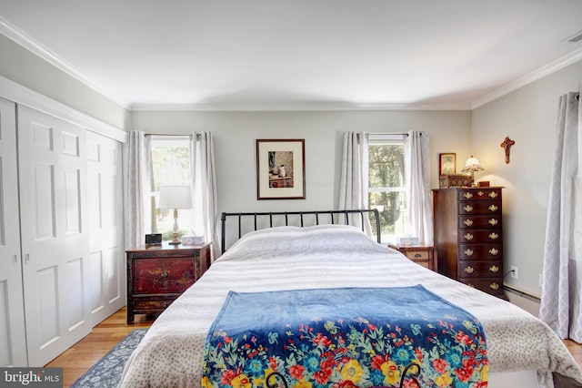 bedroom featuring light wood finished floors, visible vents, a baseboard radiator, crown molding, and a closet