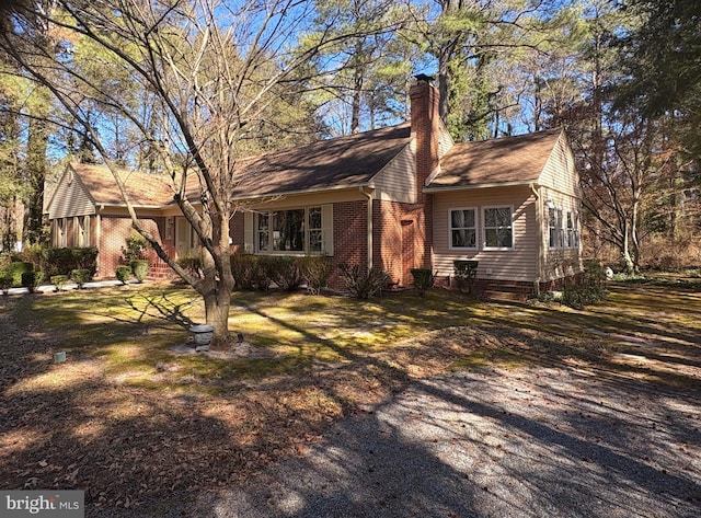 view of front of property featuring a front yard, a chimney, and brick siding