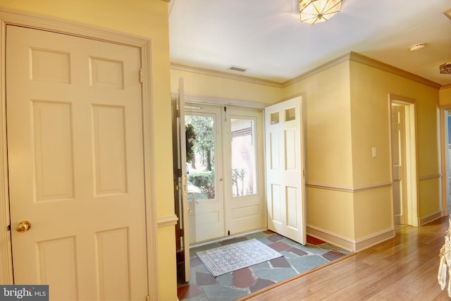 foyer with visible vents, crown molding, baseboards, and wood finished floors