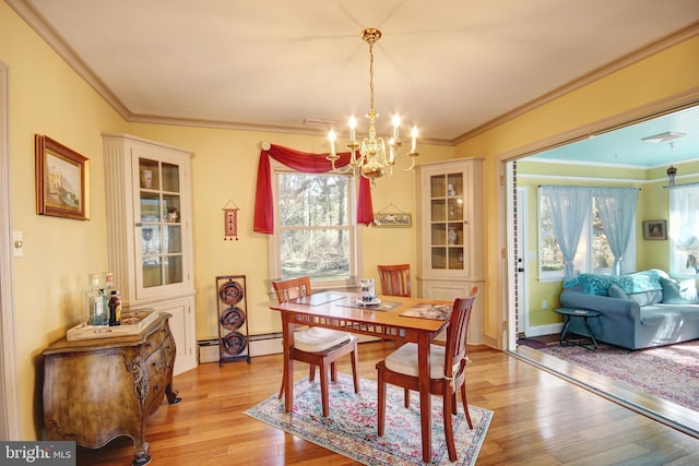 dining space with light wood-style floors, a notable chandelier, crown molding, and baseboard heating