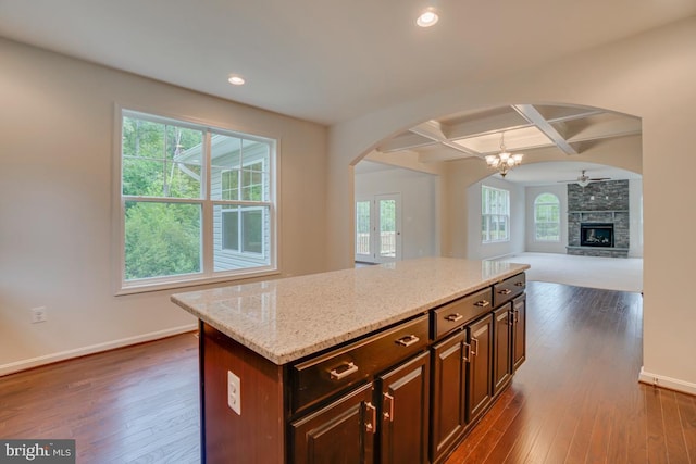 kitchen featuring coffered ceiling, baseboards, arched walkways, and dark wood finished floors