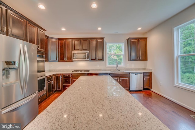 kitchen with light stone countertops, stainless steel appliances, recessed lighting, dark wood finished floors, and a sink