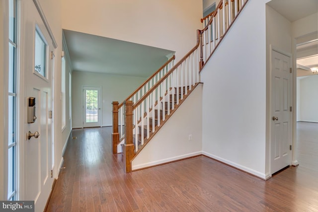 entryway with a towering ceiling, stairs, baseboards, and hardwood / wood-style flooring