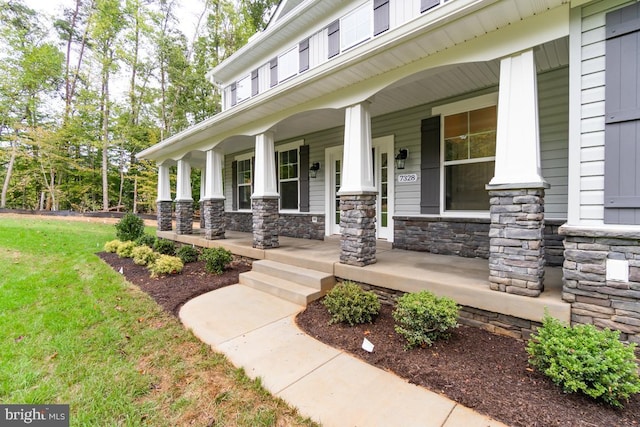 property entrance featuring stone siding, a porch, and a yard