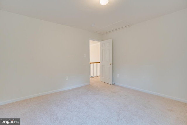 empty room featuring light carpet, baseboards, and attic access