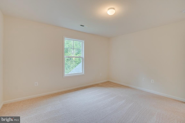 spare room with baseboards, light colored carpet, and visible vents