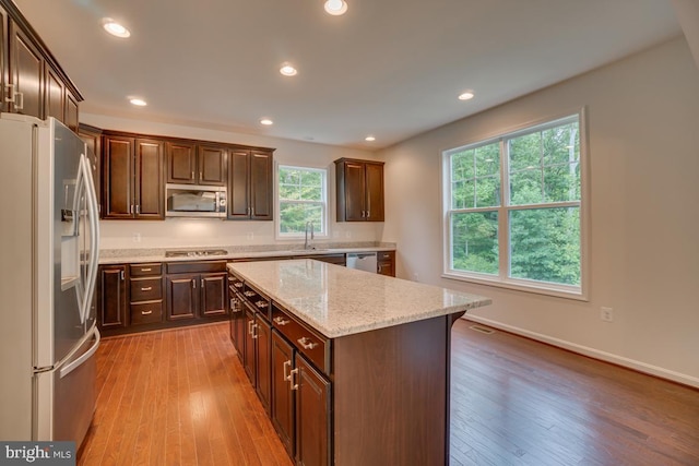 kitchen featuring dark brown cabinetry, stainless steel appliances, light wood-style floors, and a center island
