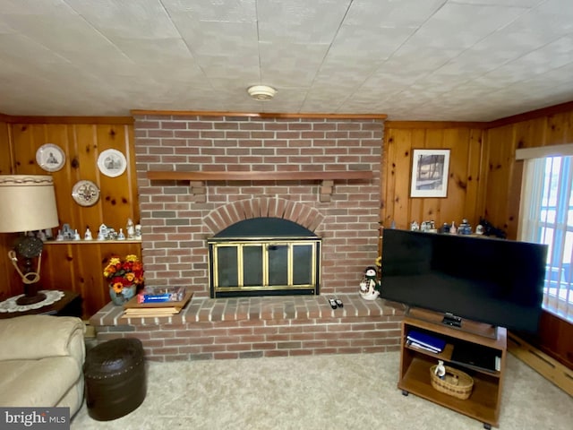 living room with a brick fireplace, carpet, and wood walls