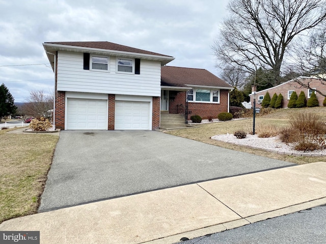 split level home with aphalt driveway, a front yard, brick siding, and an attached garage