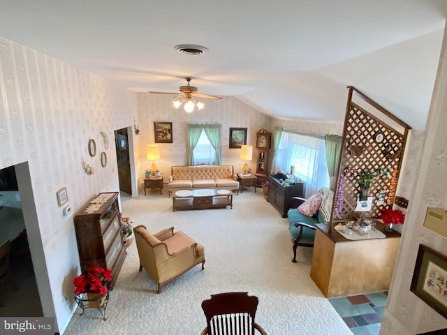 carpeted living area featuring wallpapered walls, visible vents, vaulted ceiling, and a ceiling fan