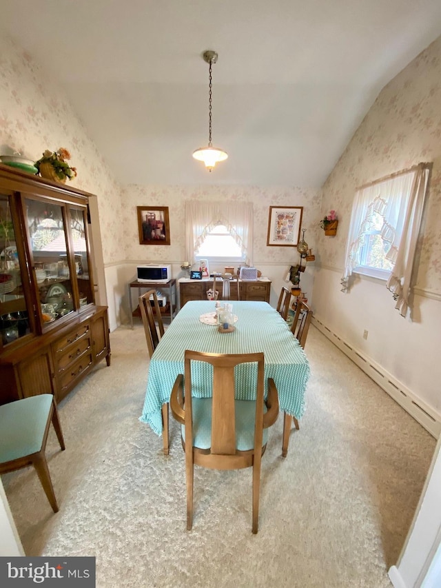 carpeted dining area featuring lofted ceiling, wallpapered walls, a healthy amount of sunlight, and a baseboard heating unit