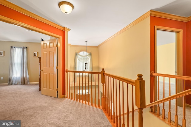 hallway with carpet floors, baseboards, ornamental molding, and an upstairs landing