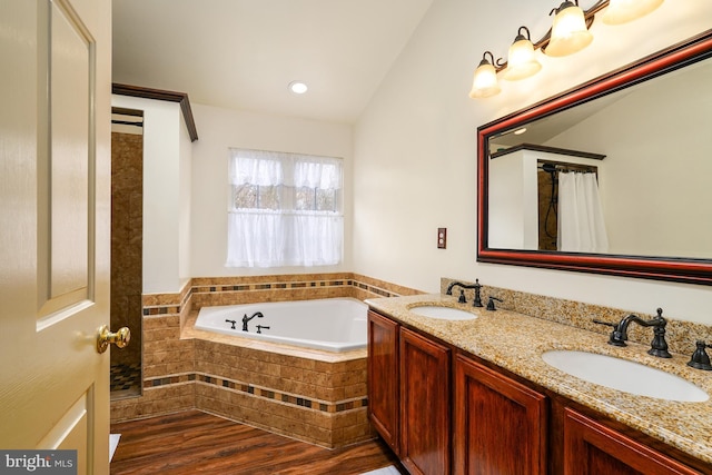 bathroom with vaulted ceiling, wood finished floors, a sink, and a bath