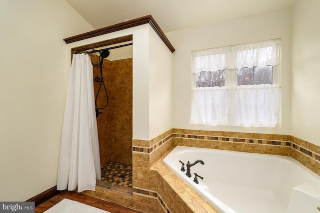 bathroom with a healthy amount of sunlight, a bath, and tiled shower