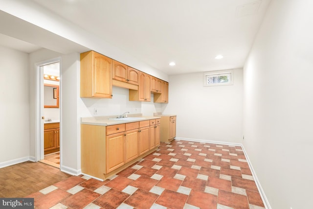 kitchen with light brown cabinets, recessed lighting, a sink, and baseboards