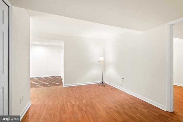 spare room with baseboards and light wood-style floors