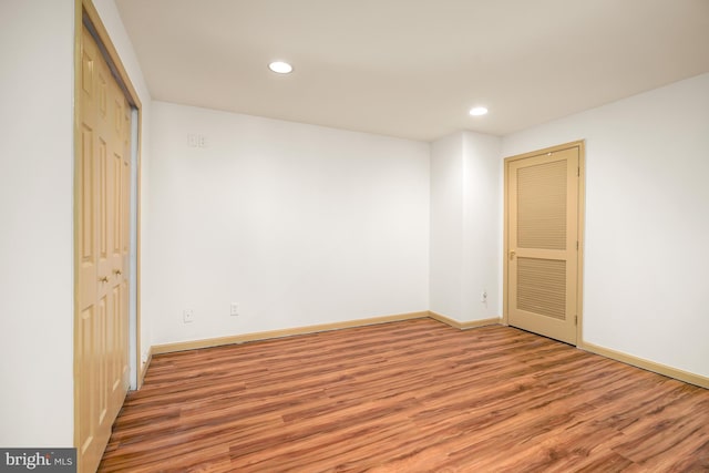 unfurnished bedroom with recessed lighting, a closet, baseboards, and wood finished floors