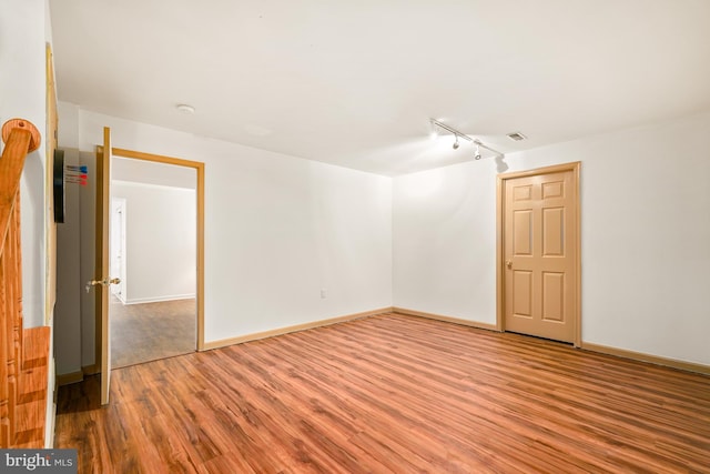 empty room with rail lighting, visible vents, baseboards, and wood finished floors