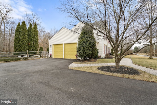 view of property exterior with driveway and fence