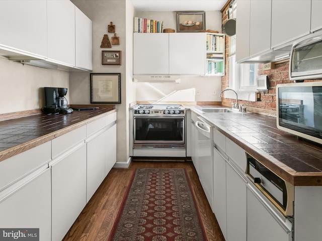 kitchen with white cabinets, tile countertops, stainless steel microwave, under cabinet range hood, and gas stove