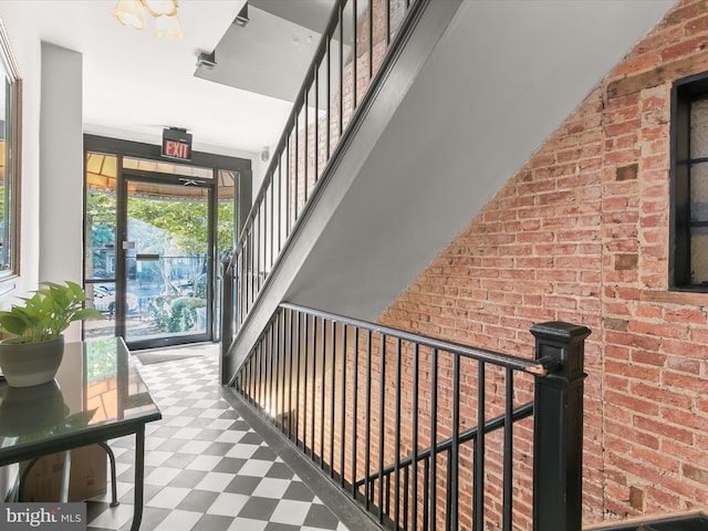 interior space featuring stairs, brick wall, and tile patterned floors