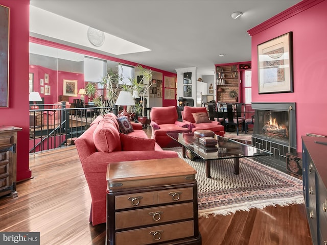 living room with a warm lit fireplace and wood finished floors