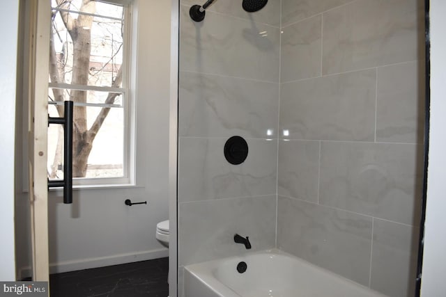 full bathroom featuring toilet, baseboards, and shower / washtub combination