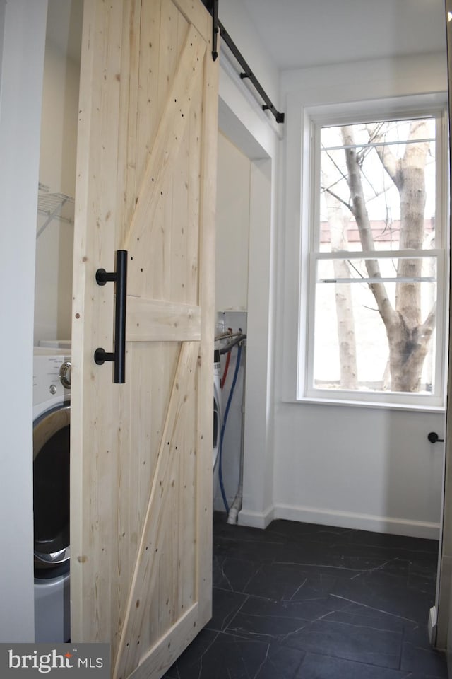 clothes washing area featuring a barn door, washer / clothes dryer, baseboards, and laundry area