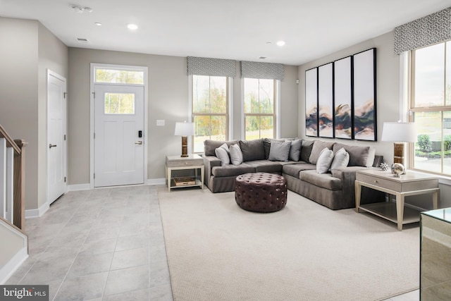 living room featuring light tile patterned floors, plenty of natural light, and stairs