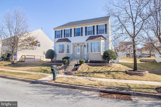 view of front of property with entry steps, a standing seam roof, metal roof, and a front lawn