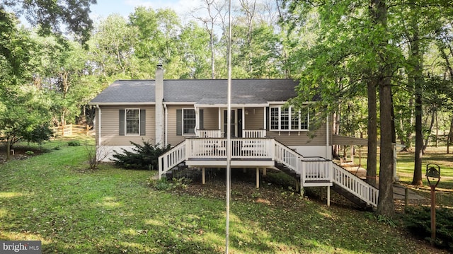 view of front facade with a shingled roof, a chimney, stairway, a deck, and a front lawn