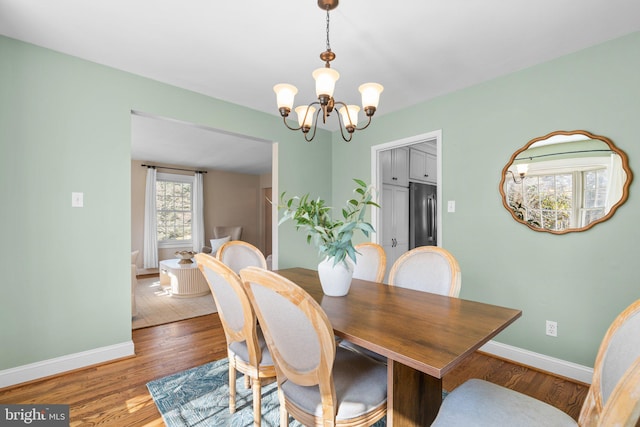 dining room featuring an inviting chandelier, baseboards, and light wood-style floors