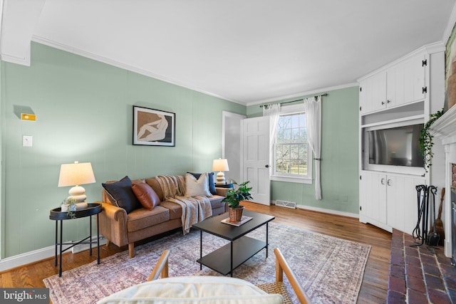 living area with dark wood-type flooring, baseboards, visible vents, and ornamental molding