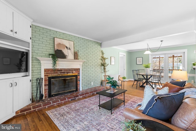 living room featuring wood finished floors, a fireplace, and crown molding