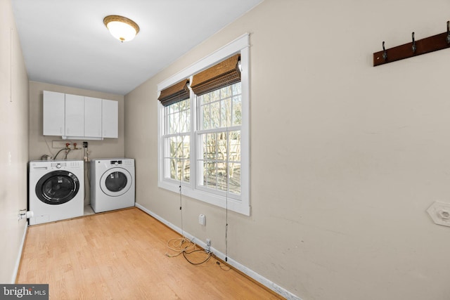 laundry room featuring light wood finished floors, baseboards, cabinet space, and washer and clothes dryer